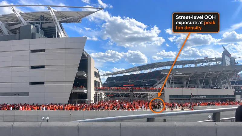 Pedicab on the street outside Paycor Stadium as fans in orange fill the stands, marked as street-level exposure at peak fan density
