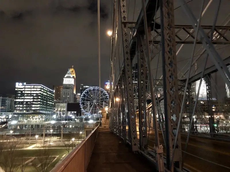 Walkway of the Roebling Suspension Bridge at night with the Cincinnati skyline beyond